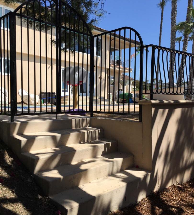 New colored concrete steps and fence over a new retaining wall. Pacificland Constructors