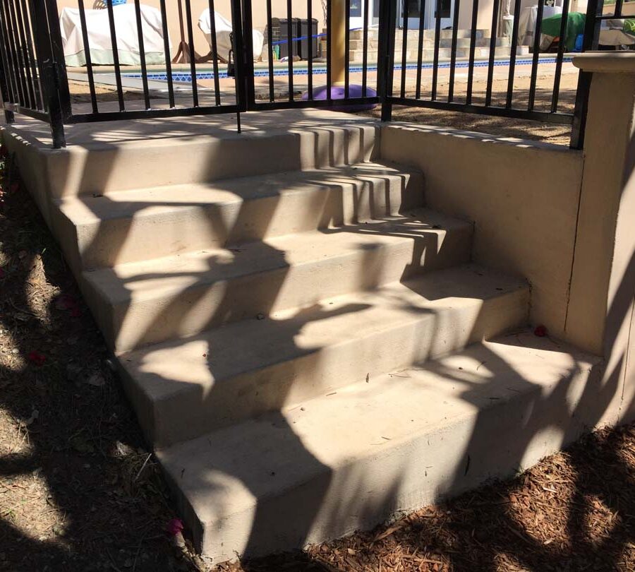 New colored concrete steps and fence over a new retaining wall. Pacificland Constructors