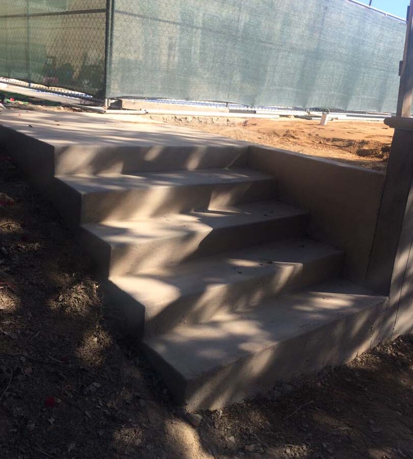 Construction of new steps leading to the elevated backyard patio held up by a retaining wall. Pacificland Constructors