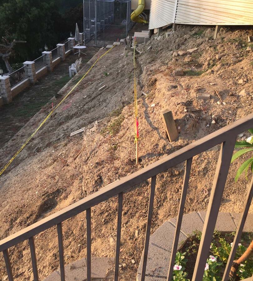 Construction of a new retaining wall long the slope of the hill. Pacificland Constructors