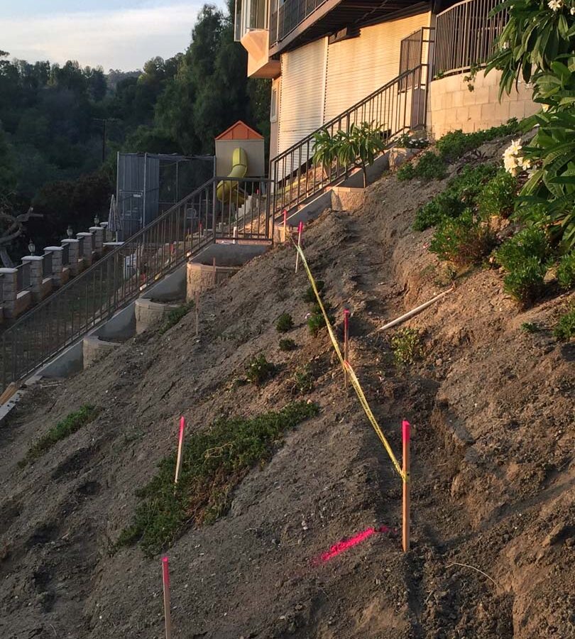 Construction of a new retaining wall long the slope of the hill. Pacificland Constructors