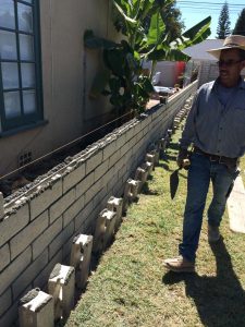 Martin, founder of Pacificland, laying slump block for a home’s side yard. This is a great option to raise the value of your home and create more private living space.