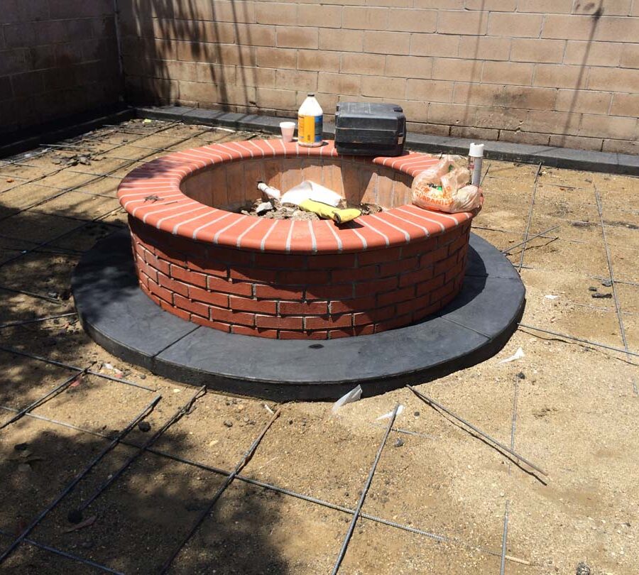 Construction of a new Brick fire pit and dark concrete ribbon for a home. Pacificland Constructors