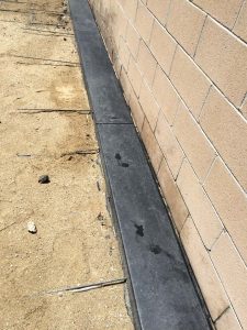 New dark concrete ribbon connected to a concrete patio. Pacificland Constructors