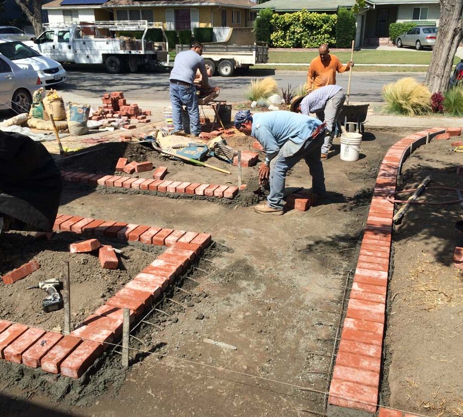 Construction of a new stamped concrete walkway with brick ribbon with manufactured white stained brick ribbons that will create a vintage look. Pacificland Constructors