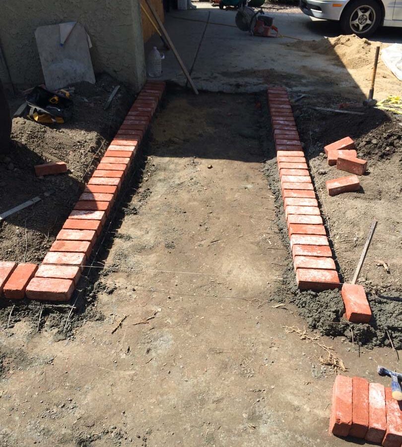 Construction of a new stamped concrete walkway with brick ribbons that are manufactured white stains to create a vintage look. Pacificland Constructors