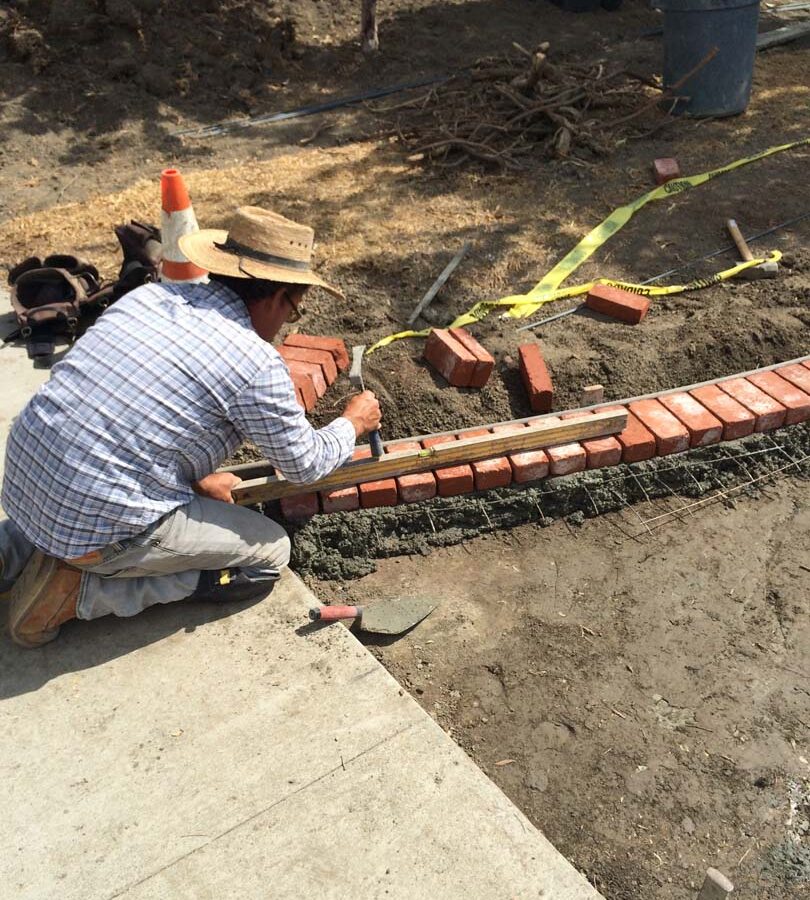 Construction of a new stamped concrete walkway with brick ribbons that are manufactured white stains to create a vintage look. Pacificland Constructors