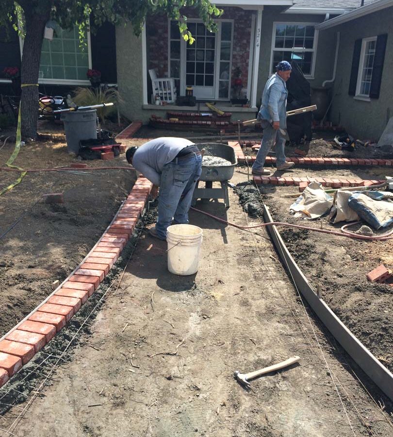 Construction of a new stamped concrete walkway with brick ribbons that are manufactured white stains to create a vintage look. Pacificland Constructors