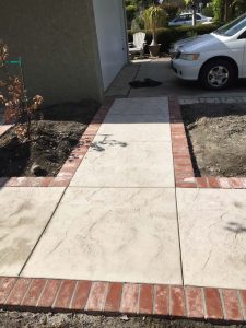 New stamped concrete walkway with brick ribbon with manufactured white stained brick ribbons that creates a vintage look. Pacificland Constructors