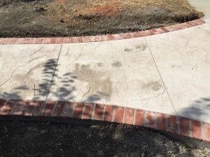 Stamped concrete with brick ribbons and handmade joints.