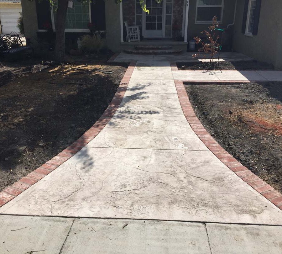 Colored stamped concrete with brick ribbons and handmade joints.