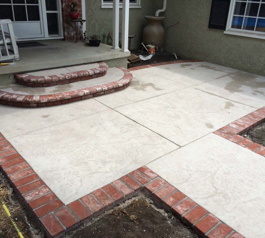 New stamped concrete front patio with brick ribbon with manufactured white stained brick ribbons and steps that creates a vintage look. Pacificland Constructors