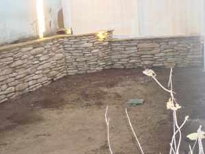 New stone veneer is placed over precision block wall. This wall is capped off with flagstone.