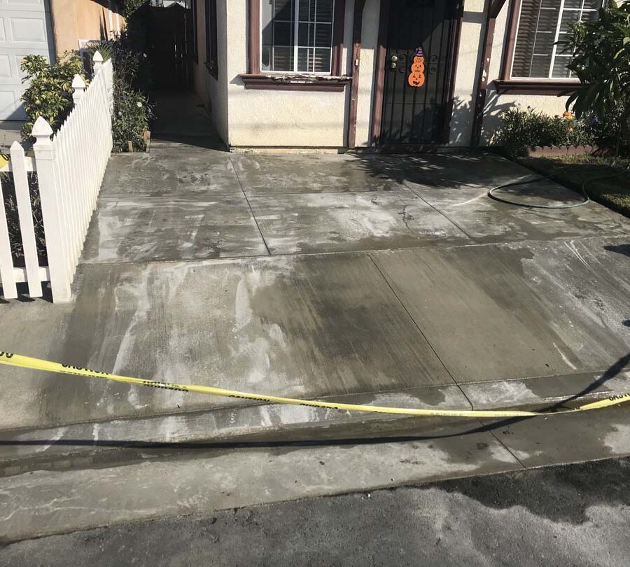 Finished concrete driveway with broomswept finish and hand scorched joints. Pacificland Constructors