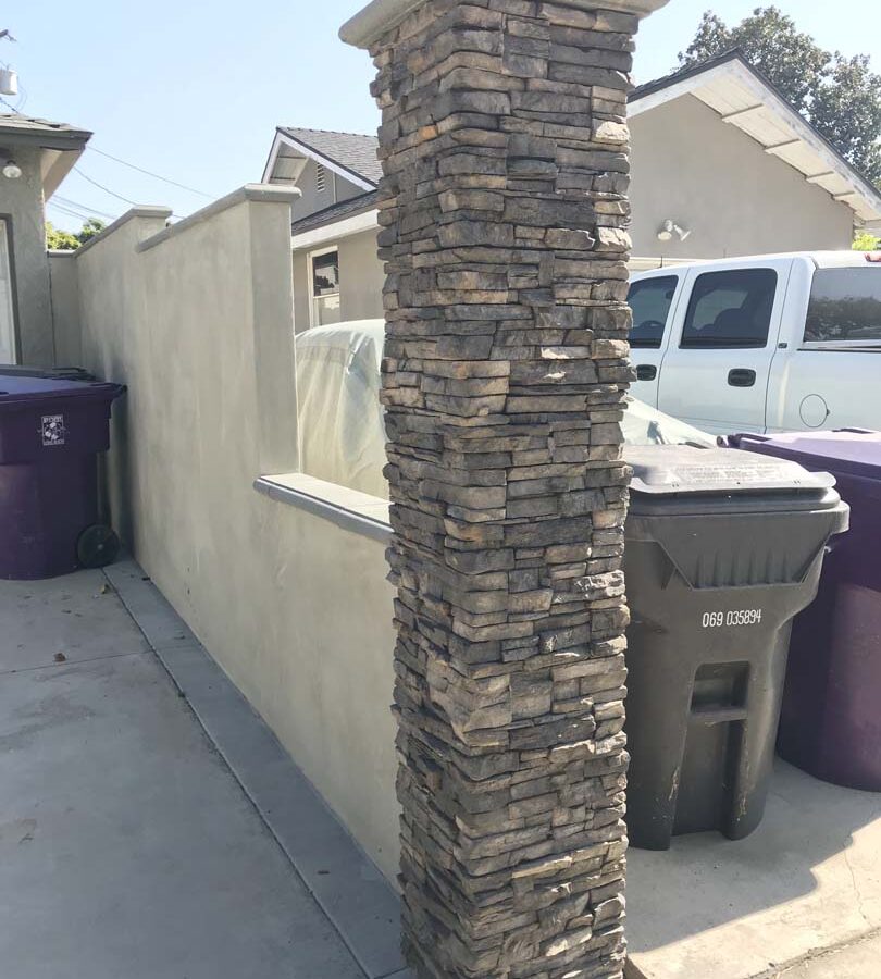 Pilaster to the edge of the property line. Covered with stone veneer and topped off with a stepstone cap. Pacificland Constructors