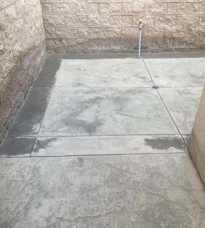 Gray stamped concrete with soffcut joints, a darker colored concrete ribbon, and a new CMU split faced block wall along the property perimeter. Pacificland Constructors