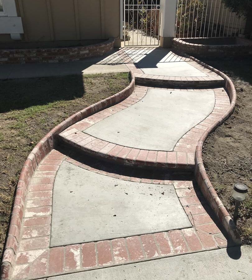 New beautiful curved front yard concrete walkway and steps with brick ribbon and bull-nosed steps. Pacificland Constructors