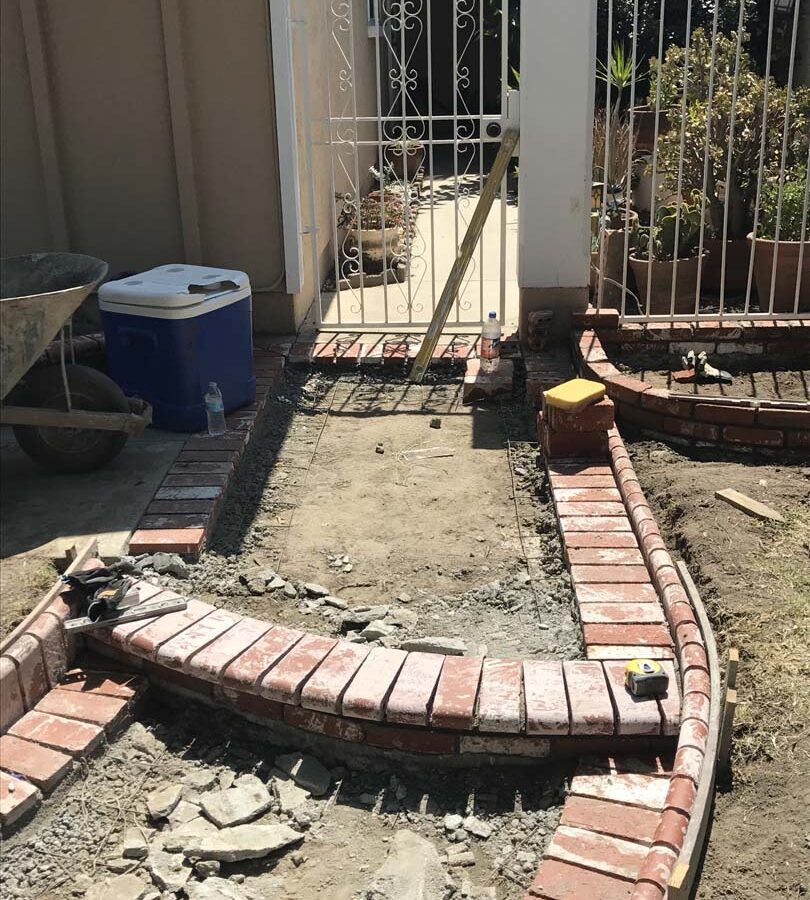 Construction of a new beautiful curved front yard concrete walkway with brick ribbon bull-nosed steps. Pacificland Constructors