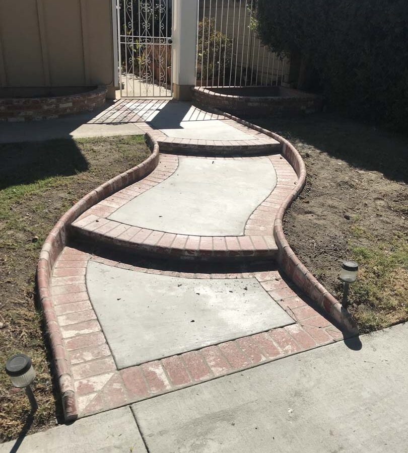 New beautiful curved front yard concrete walkway and steps with brick ribbon and bull-nosed steps. Pacificland Constructors