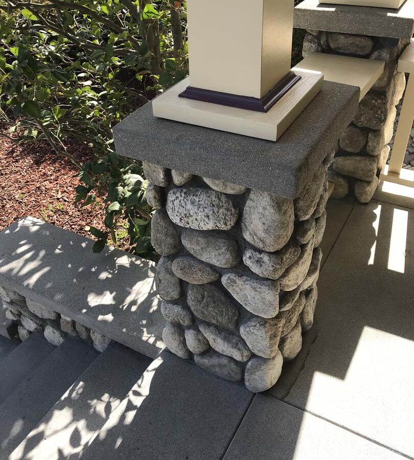 Cobble stone covered short wall topped off with a concrete poured wall cap. Pacificland Constructors