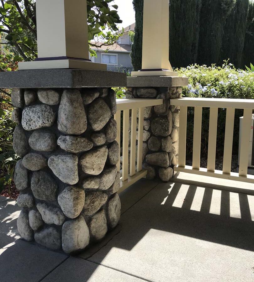 Cobble stone covered short wall topped off with a concrete poured wall cap. New concrete steps have a broom finish texture. Pacificland Constructors