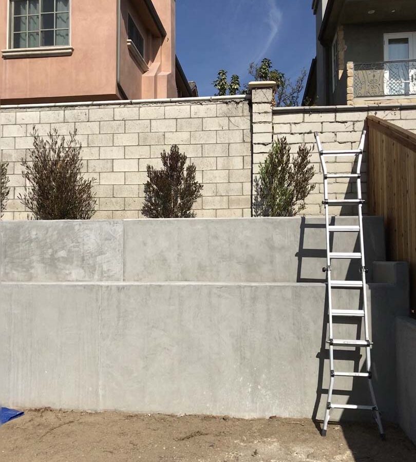 New pour in place concrete retaining wall for a backyard in Huntington Beach, CA. This retaining wall creates more flat area for the home because it holds up the differential earth elevation from the neighbor’s home. Pacificland Constructors