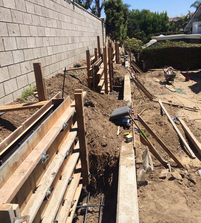 Formwork carpentry and steel reinforcement for a new concrete retaining wall for a backyard in Huntington Beach, CA. Pacificland Constructors