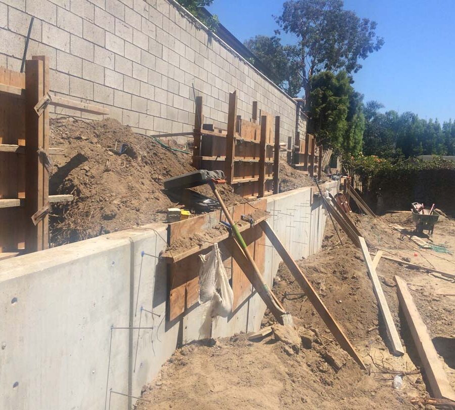 Stripping the formwork carpentry from this new concrete retaining wall for a backyard after pouring it. Pacificland Constructors