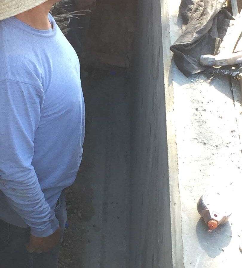 Installing a drainage system for this new retaining wall. A perforated PVC pipe is buried under the porous aggregate that will collect the water that accumulates behind the wall and drain it out. This allows the wall to maintain its structural integrity throughout the years. Pacificland Constructors