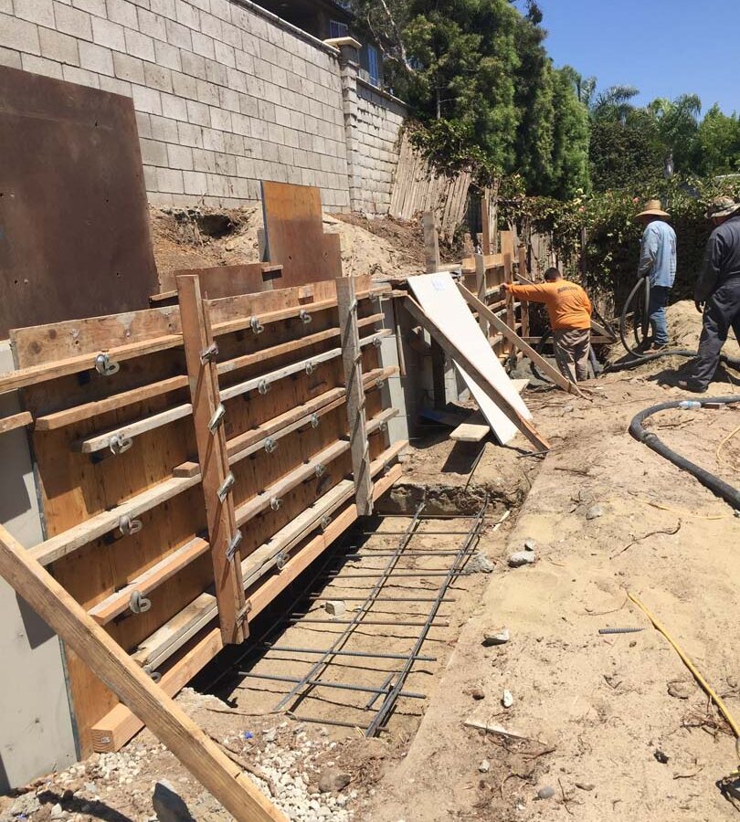 Formwork carpentry and steel reinforcement for a new concrete retaining wall for a backyard in Huntington Beach, CA. Pacificland Constructors