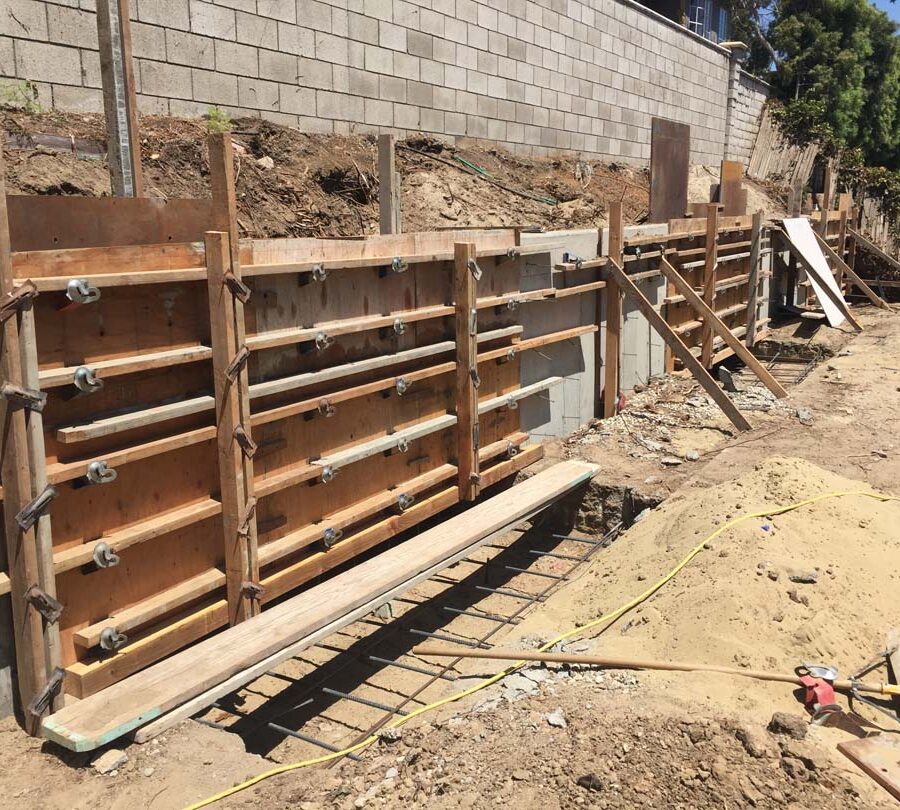 Formwork carpentry and steel reinforcement for a new concrete retaining wall for a backyard in Huntington Beach, CA. Pacificland Constructors