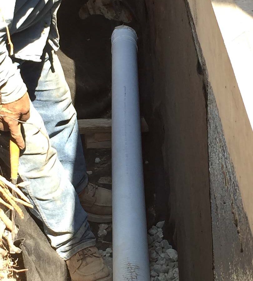 Installing a drainage system for this new retaining wall. This perforated PVC pipe is buried under a porous aggregate that will serve as a filter for water before it is collected by the PVC pipe and drained out from behind the wall. This allows the wall to maintain its structural integrity throughout the years. Pacificland Constructors