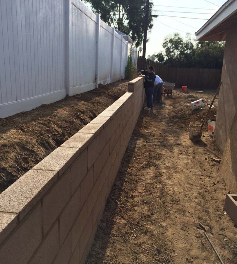 Laying a block wall caps for a new tan precision block retaining wall. Pacificland Constructors