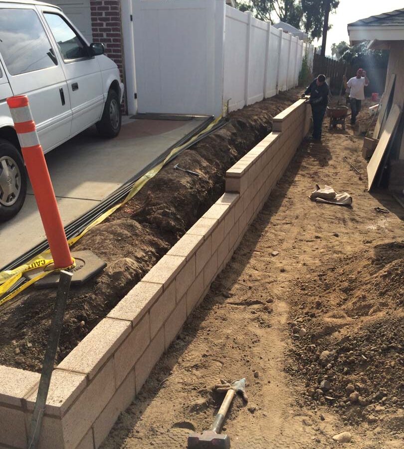 Laying a block wall caps for a new tan precision block retaining wall. Pacificland Constructors