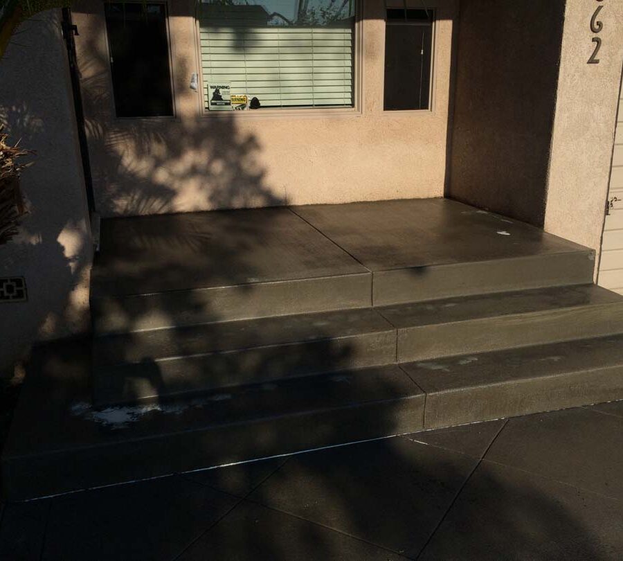 New beautiful broom swept concrete front yard porch with sealer polymer applied to it. This polymer will become transparent when dry and protect the concrete from stains while creating a somewhat reflective surface as if it were just watered. Pacificland Constructors