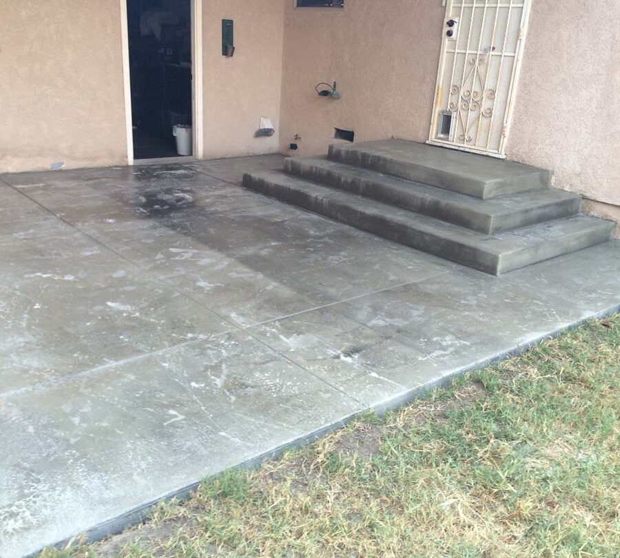 New beautiful broom swept concrete steps and backyard patio with a sealer polymer being applied to it. This polymer will become transparent when dry and protect the concrete from stains while creating a somewhat reflective surface as if it were just watered. Pacificland Constructors