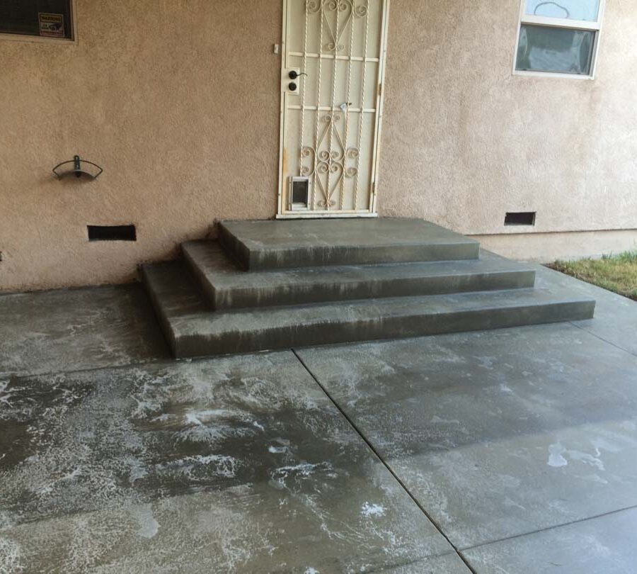 New beautiful broom swept concrete steps and backyard patio with a sealer polymer being applied to it. This polymer will become transparent when dry and protect the concrete from stains while creating a somewhat reflective surface as if it were just watered. Pacificland Constructors