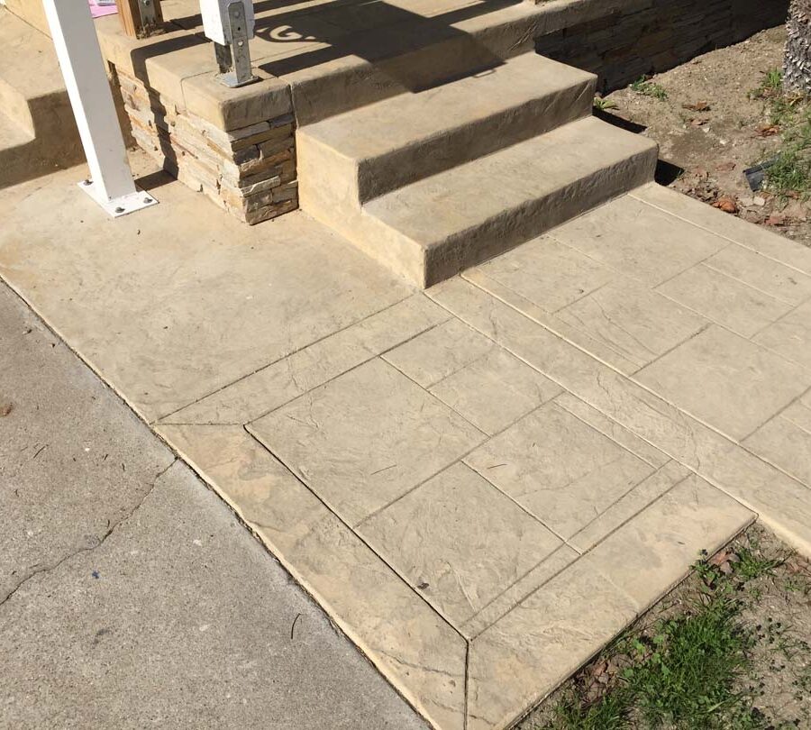 Colored stamped concrete with handmade joints. The steps also have the stamped texture and the porch face has stone veneer.