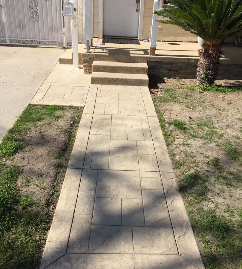 Colored stamped concrete with handmade joints. The steps also have the stamped texture and the porch face has stone veneer.