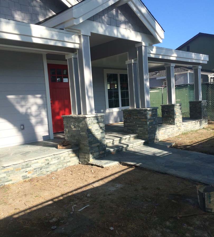 Flagstone flatwork at the entrance of a home. Artificial stone covered pilasters to create a modern theme. Pacificland Constructors