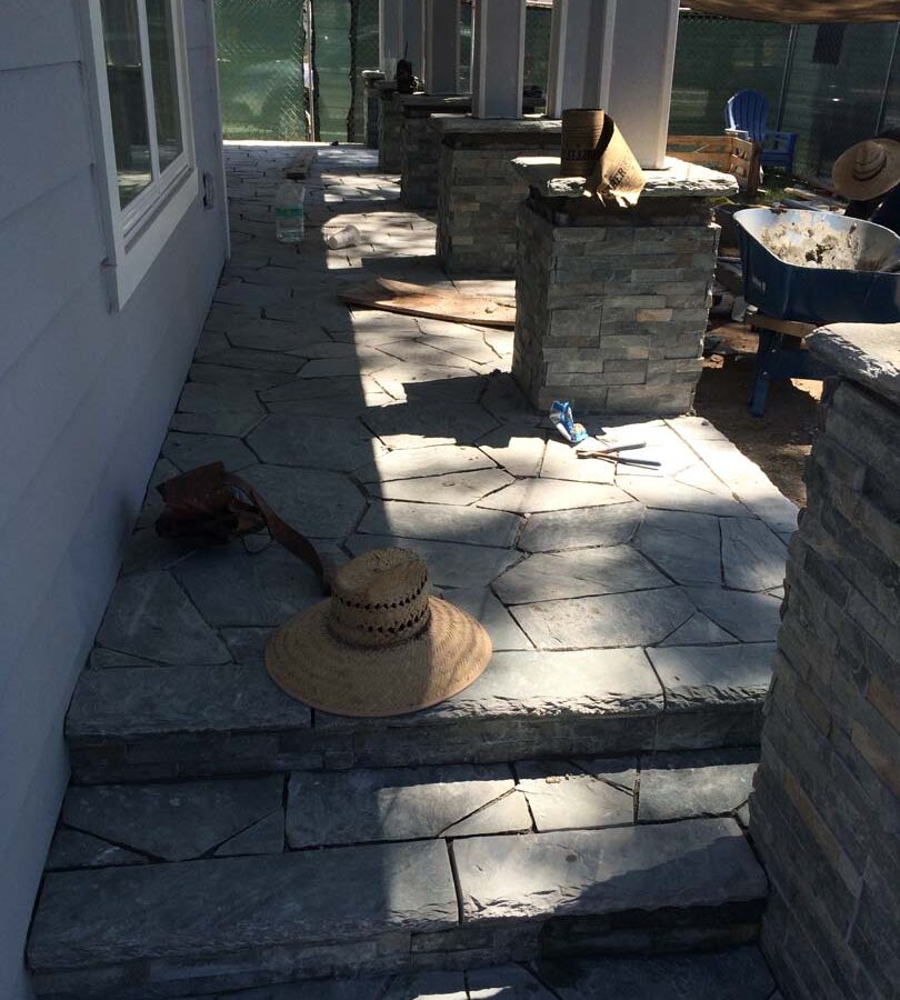 Construction of Flagstone flatwork at the entrance of a home. Artificial stone covered pilasters are intended to create a modern theme. Pacificland Constructors