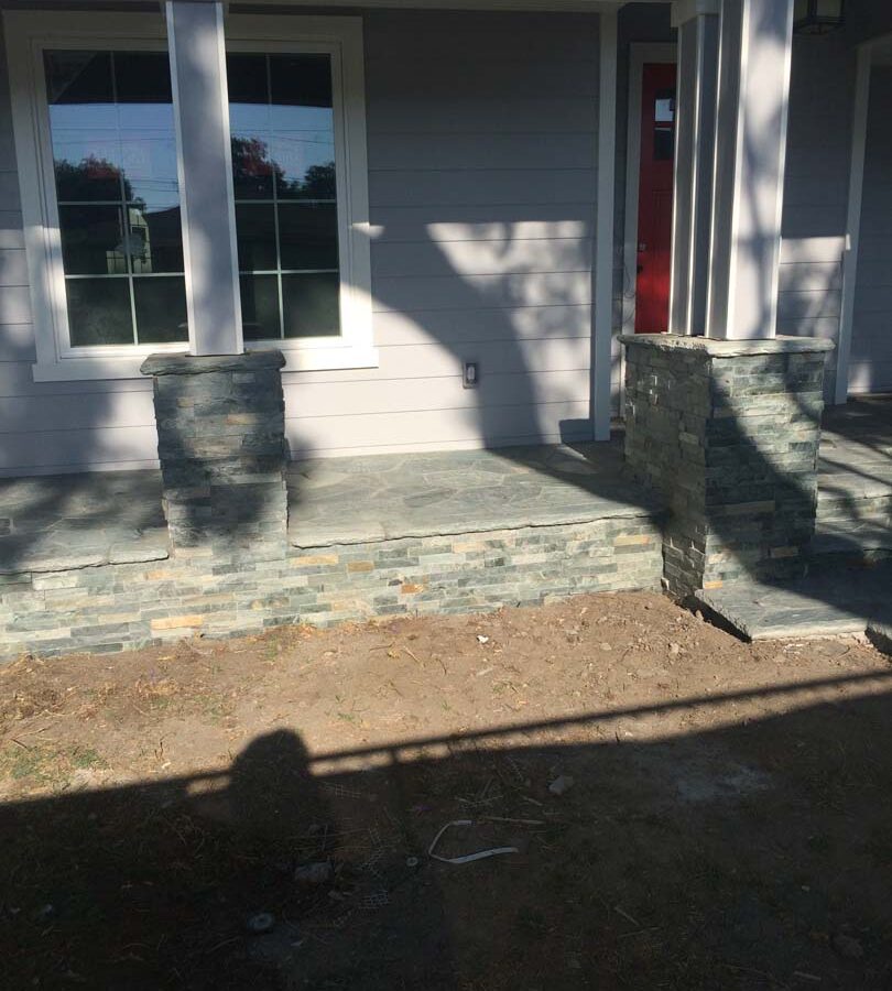 Flagstone flatwork at the entrance of a home. Artificial stone covered pilasters to create a modern theme. Pacificland Constructors