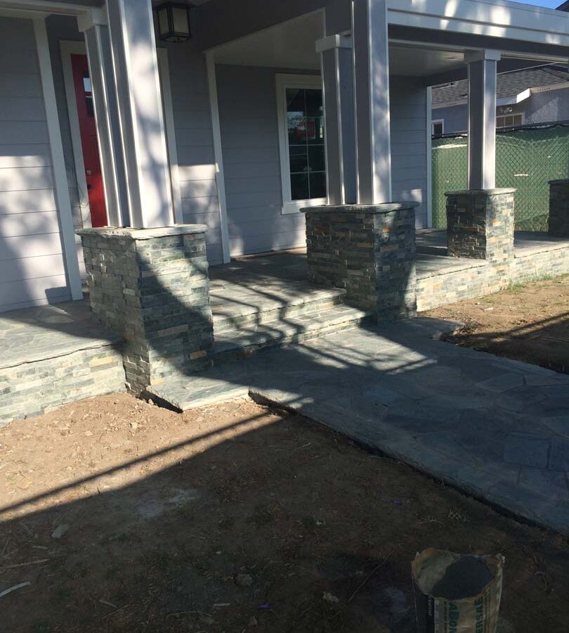 Flagstone flatwork at the entrance of a home. Artificial stone covered pilasters to create a modern theme. Pacificland Constructors