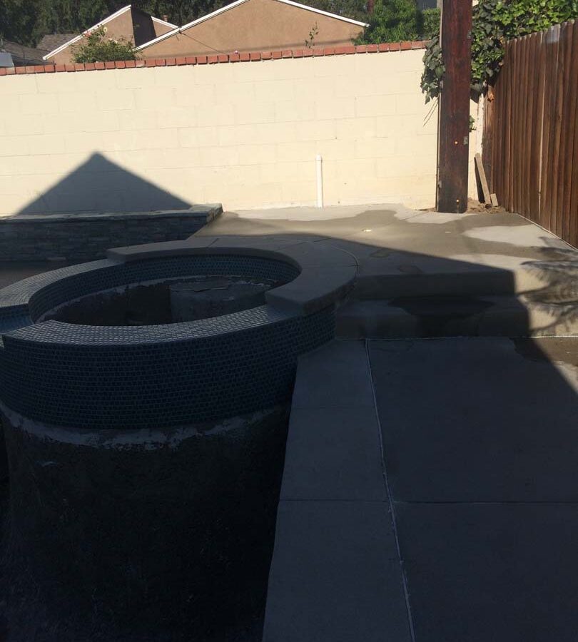 New gray concrete deck with a stone veneered planter with custom colored wall cap. Pacificland Constructors