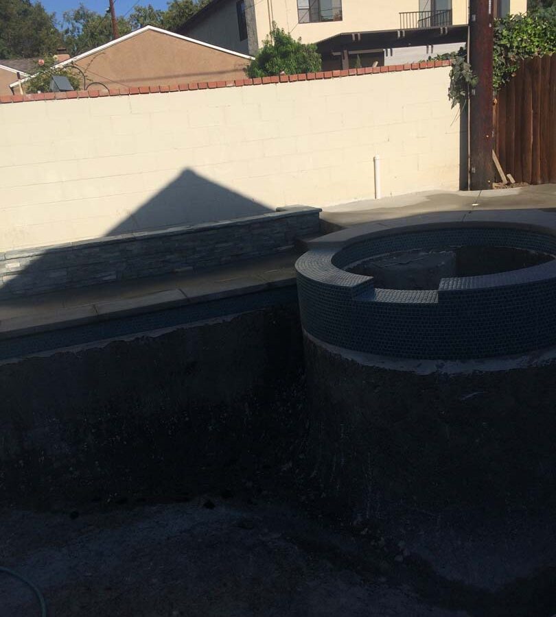 New gray concrete deck with a stone veneered planter with custom colored wall cap. Pacificland Constructors