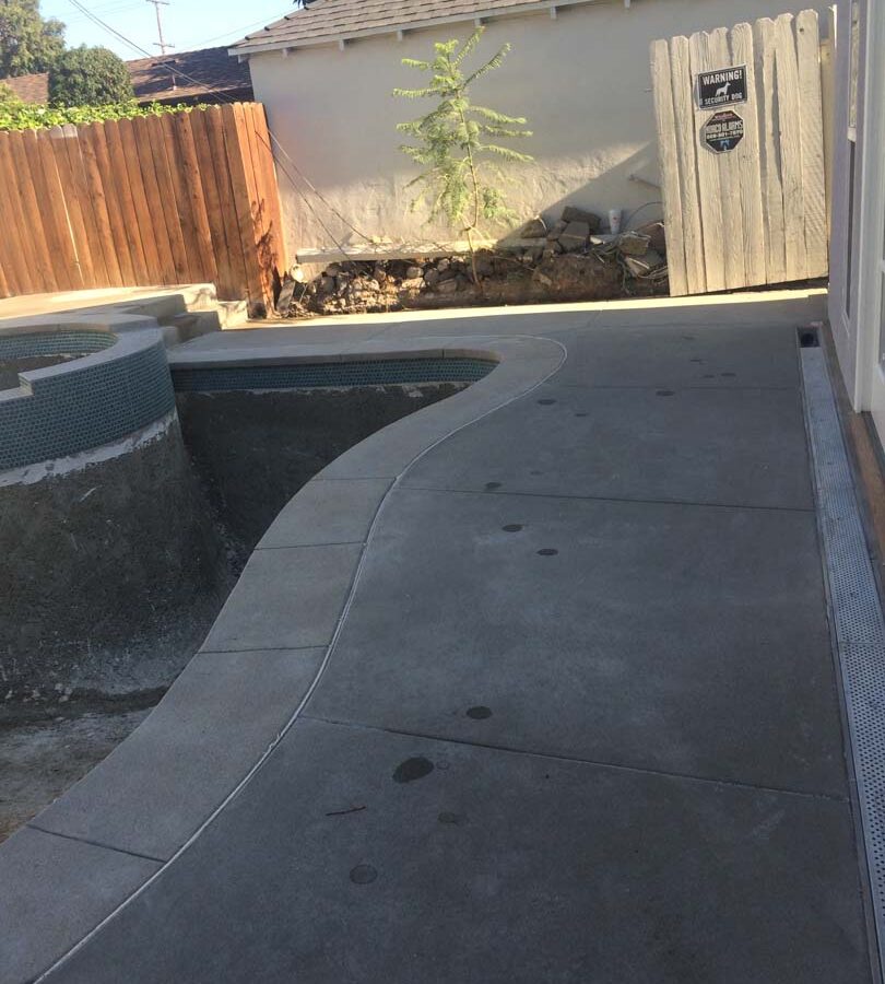 New gray concrete deck with a stone veneered planter with custom colored wall cap. Pacificland Constructors