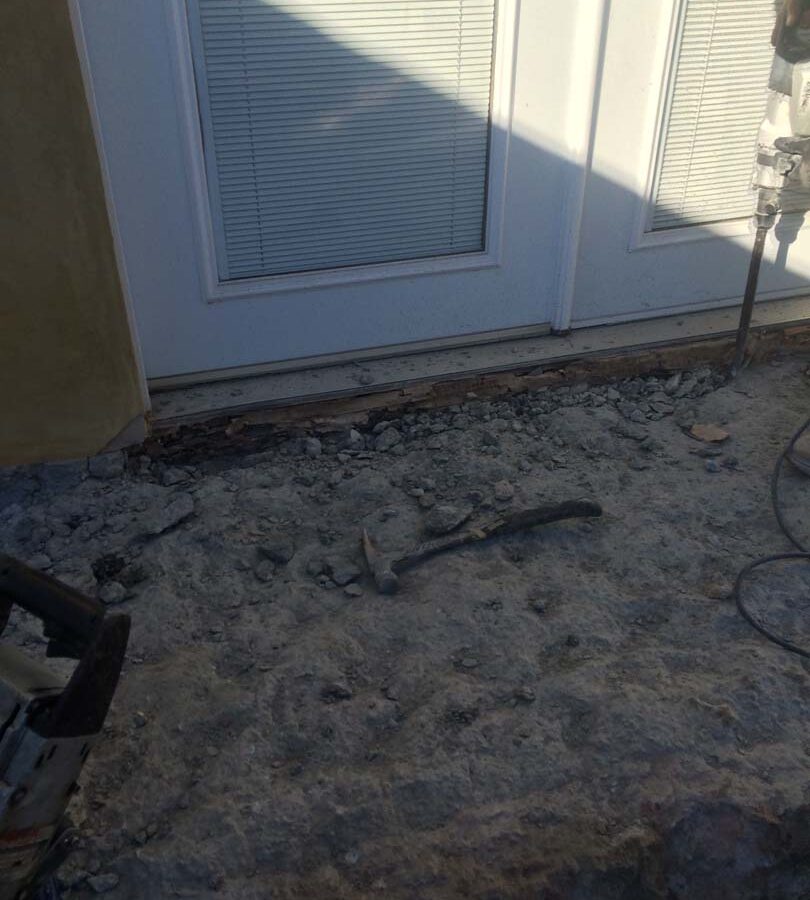 Formwork construction of new concrete porch with steps. Chipping of concrete to install sheathing and flashing that will be placed under the door to protect it. Pacificland Constructors