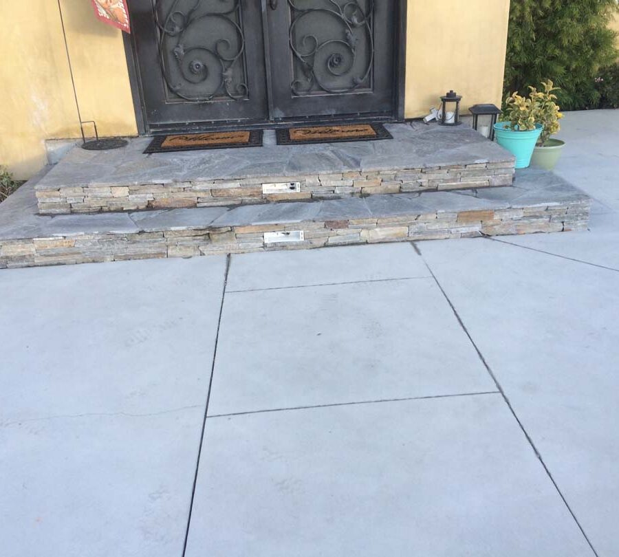 New concrete backyard patio with beautiful flagstone covered concrete steps with stone veneer and a new artisan door. Pacificland Constructors