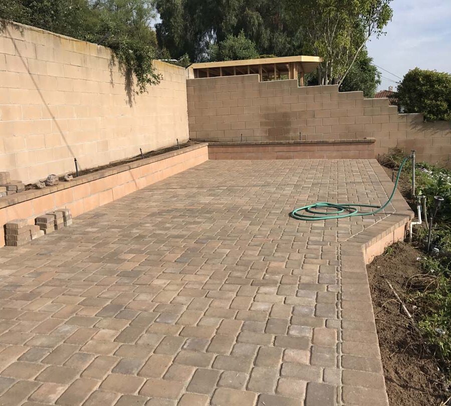 Finished paver patio with a CMU block planter. Pacificland Constructors