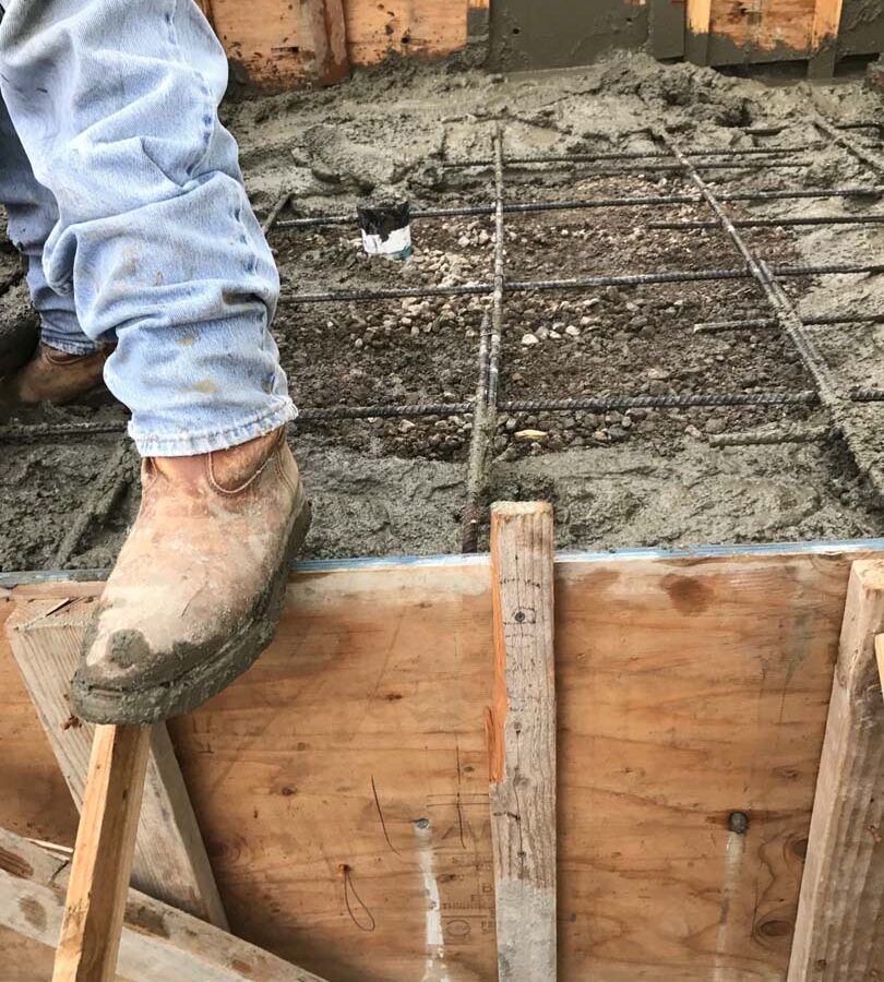 Concrete pouring of a new patio after forming, steel reinforcement, and grading. Pacificland Constructors